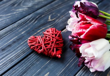 Renkli güzel pembe mor laleler ve gri ahşap masa üzerinde kırmızı kalp. Sevgililer, bahar arka plan. Çiçek boşaltmak ile sahte. Happy anneler günü, romantik natürmort, taze çiçekler