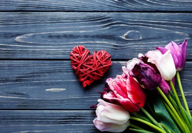 Renkli güzel pembe mor laleler ve gri ahşap masa üzerinde kırmızı kalp. Sevgililer, bahar arka plan. Çiçek boşaltmak ile sahte. Happy anneler günü, romantik natürmort, taze çiçekler