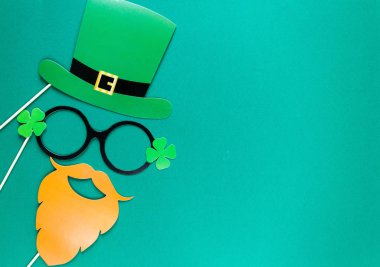 Yaratıcı st Patricks Günü yeşil arka plan. İrlandalı tatil kutlaması fotoğraf stand dekorasyonu ile düz yatıyordu bileşimi: şapka, Gözlük, papyon, dudaklar. Kopya alanı, tebrik kartı, üstten görünüm