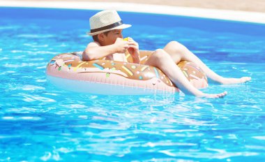 Şirin çocuk çocuk komik şişme çörek float halkası portakal ile yüzme havuzunda üzerinde. Yüzmeyi, öğrenme genç Resort'ta açık yüzme havuzunda eğlenceli var. Su oyuncaklar çocuklar için. Sağlıklı spor aktivitesi, tatil 