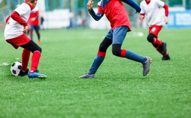 Kırmızı ve beyaz spor giyim çocuklar yeşil çim sahada futbol oynar. Gençlik futbol oyunu. Çocuk spor yarışması, çocuk eğlence açık, Etkinlikler, eğitim