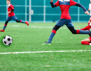 Kırmızı ve beyaz spor giyim çocuklar yeşil çim sahada futbol oynar. Gençlik futbol oyunu. Çocuk spor yarışması, çocuk eğlence açık, Etkinlikler, eğitim