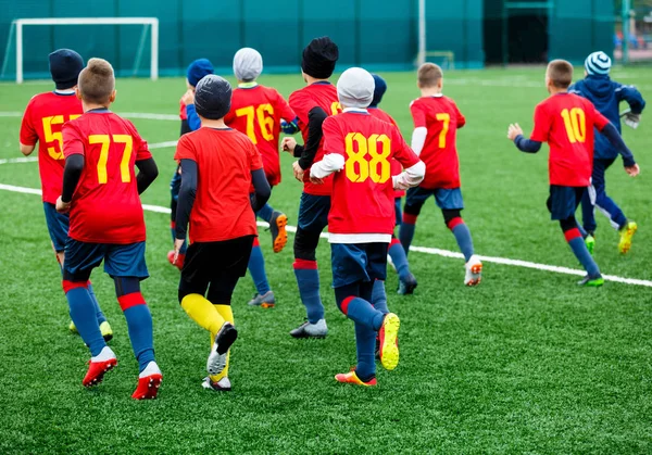 赤いスポーツウェアで少年サッカーの緑の芝生のフィールドで実行します 青年フットボールの試合 子供スポーツ競争 屋外の子供の演劇 トレーニング — ストック写真