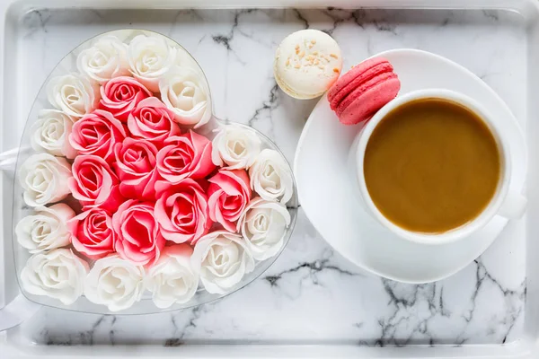 cup of coffee, macarons and roses on granite background