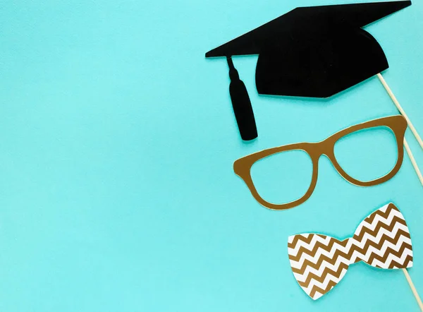 Creative background with photobooth props for graduation: hats, diploma, glasses, lips on bright blue paper background. Education, study concept.