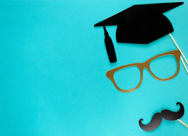 Creative background with photobooth props for graduation: hats, diploma, glasses, lips on bright blue paper background. Education, study concept.