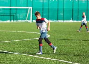 Kırmızı beyaz spor futbol sahası üzerinde çalışan çocuklar. Genç futbolcular top sürmek ve oyunda futbol topu tekmelemek. Eğitim, aktif yaşam tarzı, spor, çocuk etkinlik kavramı 