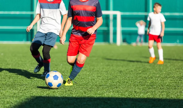少年サッカーのフィールドで実行している赤白のスポーツウェア 若い選手はドリブルし ゲームでサッカー ボールを蹴る トレーニング アクティブなライフ スタイル スポーツ 子供の活動の概念 — ストック写真
