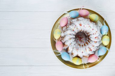 Mutlu Paskalya! Altın tepsi plaka pasta ve el ahşap masada renkli yumurta boyalı. Kapat şunu. Paskalya için dekorasyon, şenlikli arka plan.