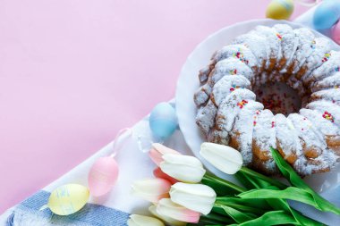 Mutlu Paskalya! Kek ve el boyalı renkli yumurta, lale ve beyaz arka planda büyük plaka. Kapat şunu. Paskalya için dekorasyon, şenlikli arka plan.