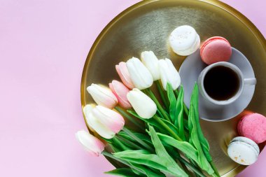 Macaroons, lale, pembe arka planda kahve bardağı ile altın tepsi plaka. Kapat şunu. Anneler günü için dekorasyon, Uluslararası Kadınlar günü, şenlikli arka plan.