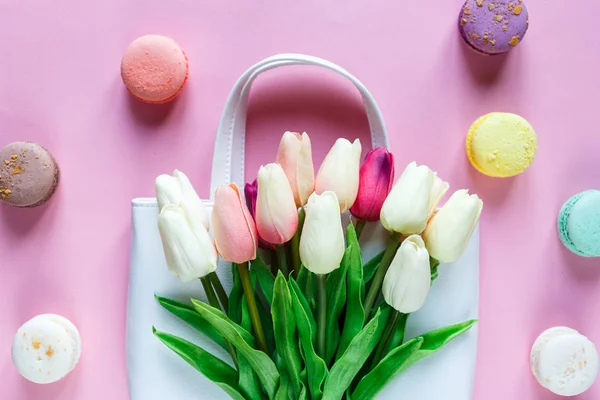 pink tulips and macaroons on a pink background. top view.