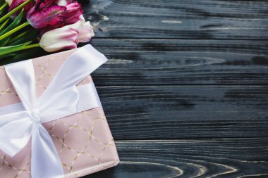 Taze mor pembe parlak laleler ve ahşap arka plan üzerinde fiyonklu hediye paketi. Anneler günü, Dünya Kadınlar Günü için Festival arka plan