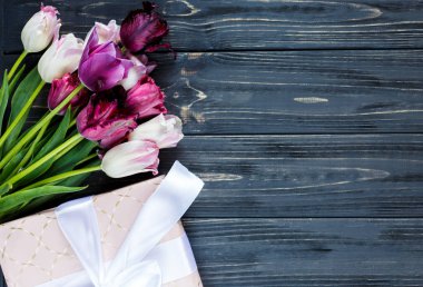 Taze mor pembe parlak laleler ve ahşap arka plan üzerinde fiyonklu hediye paketi. Anneler günü, Dünya Kadınlar Günü için Festival arka plan