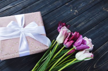 Taze mor pembe parlak laleler ve ahşap arka plan üzerinde fiyonklu hediye paketi. Anneler günü, Dünya Kadınlar Günü için Festival arka plan