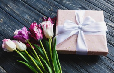 Taze mor pembe parlak laleler ve ahşap arka plan üzerinde fiyonklu hediye paketi. Anneler günü, Dünya Kadınlar Günü için Festival arka plan