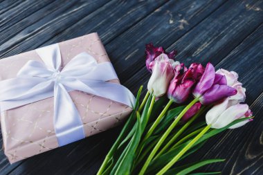 Taze mor pembe parlak laleler ve ahşap arka plan üzerinde fiyonklu hediye paketi. Anneler günü, Dünya Kadınlar Günü için Festival arka plan