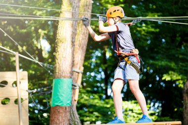 Genç yakışıklı ip eğlence parkı ekipmanları tırmanma kask içinde. Yaz kampı, tatil kavramı. Aktif yaşam tarzı 