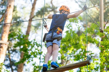 Genç yakışıklı ip eğlence parkı ekipmanları tırmanma kask içinde. Yaz kampı, tatil kavramı. Aktif yaşam tarzı 