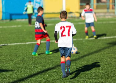 Kırmızı beyaz spor futbol sahası üzerinde çalışan çocuklar. Genç futbolcular top sürmek ve oyunda futbol topu tekmelemek. Eğitim, aktif yaşam tarzı, spor, çocuk etkinlik kavramı 
