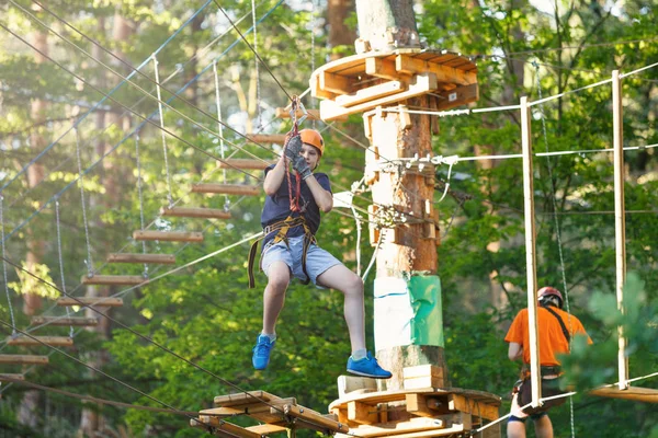 Beyaz tişörtlü sportif, genç, sevimli çocuk macera halat Parkı kask içinde ve yaz aylarında parktaki güvenli donanımları zamanını geçiriyor. Aktif yaşam tarzı kavramı