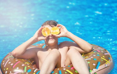 Yüzme havuzunda mutlu sevimli küçük çocuk genç. Aktif oyunlar su, tatil, tatil konsepti. Çikolatalı çörek. Çocuklar için serin eğlenceli yaz tatili.