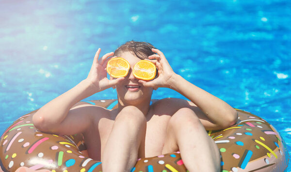 Happy cute little boy teenager in swimming pool. Active games on water, vacation, holidays concept. Chocolate donut. Cool fun summer holidays for children.