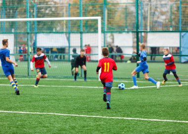 Çocuklar için futbol eğitimi. Futbol sahasında mavi kırmızı spor kıyafetine sahip çocuklar. Genç futbolcular maça ve kick Ball oyunda. Eğitim, aktif yaşam tarzı, spor, çocuk aktivite konsepti 