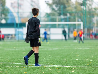 Kaleci topu tekmeliyor. Genç futbolcular maça ve Kick futbol topu oyunda. Futbol sahasında çalışan kırmızı mavi spor kıyafetine sahip çocuklar. Eğitim, aktif yaşam tarzı, spor, çocuk aktivite konsepti