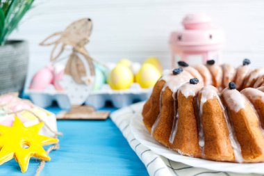 Mavi arka planda havlu üzerinde pasta ve el boyalı renkli yumurta, büyük plaka. Kapat şunu. Paskalya için dekorasyon, şenlikli arka plan. Mutlu Paskalya!