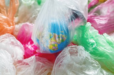 globe in a plastic bag on the background of multi-colored plastic bags