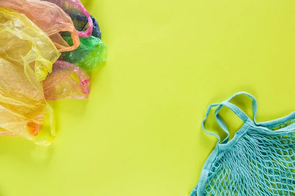 eco bag with plastic bags on green background