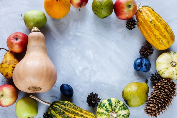 Pumpkins, pears, plums, apples on the table, top view, free space for text. Thanksgiving day composition of vegetables and fruits on gray background. Autumn harvest concept