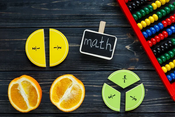 五颜六色的数学分数和橙色作为样品在黑暗的木制背景或桌子上 有趣的创意有趣的数学为孩子们 回到学校的概念 几何和数学材料 — 图库照片