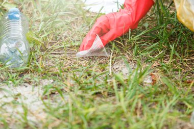 Eldivenli beyaz tişörtlü çocuk sahilde ki mavi pakette çöp ve plastik şişeleri topluyor. Genç gönüllü. Çevre koruma, çevre kavramını koruma. 