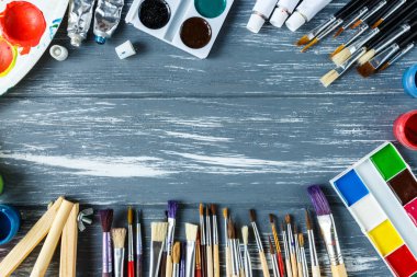 Ressam fırçalarını, paletleri ve suluboyaları grunge gri ahşap arka planda kapatın. Çok renkli boyalar seti.