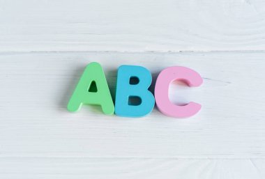 Beyaz ahşap arka planda ABC olan çok renkli ahşap harfleri kapat. Alfabe çalışmak için oyuncak seti. Eğitim, okul konseptine geri dönelim. Üst görünüm, alanı kopyala