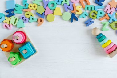 Çok renkli tahta oyuncak küpleri, piramit, harfler, beyaz ahşap arka planda numaralar. Anaokulunda, anaokulunda oyun oynamak için renkli oyuncaklar ayarla. Kapat, üst görünüm, boşluğu kopyala.