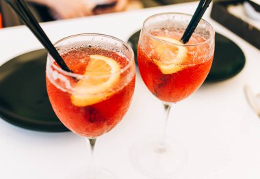Masada portakallarla süslenmiş yakın çekimli kokteyl bardakları. Kafede buzlu ve pipetli renkli pembe meşrubatlar
