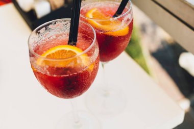Masada portakallarla süslenmiş yakın çekimli kokteyl bardakları. Kafede buzlu ve pipetli renkli pembe meşrubatlar.