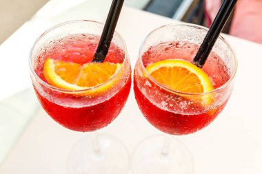 Masada portakallarla süslenmiş yakın çekimli kokteyl bardakları. Kafede buzlu ve pipetli renkli pembe meşrubatlar