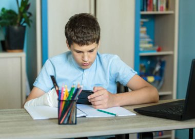 Mavi gömlekli şirin bir çocuk odasında, bilgisayarının yanında oturuyor ve ders çalışıyor. Kulaklık takan genç ev ödevi yapıyor, dinleme dersi alıyor. Ev, uzaklık eğitimi, çocukların kişisel eğitimi..