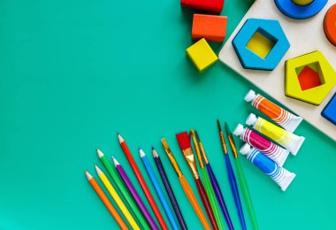 Tahta oyuncaklar, kavis, küp, fırça, yeşil arka planda şekil ayırıcı tahtası. Okul geçmişine dönelim. Kapatın. Üst görünüm, boşluğu kopyala. Anaokulu, anaokulu çocukları için eğitici oyunlar