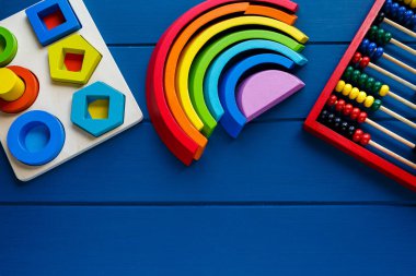 Tahta oyuncaklar, hesap rafı, klasik mavi arka planda şekil ayırıcı tahtası. Okul geçmişine dönelim. Kapatın. Üst görünüm, boşluğu kopyala. Anaokulu, anaokulu çocukları için eğitici oyunlar.