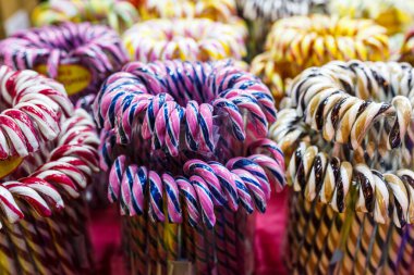 Noel ışıkları arka planında çok renkli baston şekerler. Noel panayırında lolipoplar, kış tatilleri. Kapat.