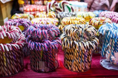 Noel ışıkları arka planında çok renkli baston şekerler. Noel panayırında lolipoplar, kış tatilleri. Kapat..