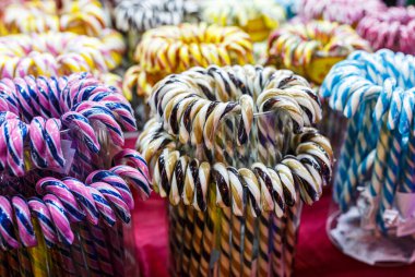 Noel ışıkları arka planında çok renkli baston şekerler. Noel panayırında lolipoplar, kış tatilleri. Kapat.