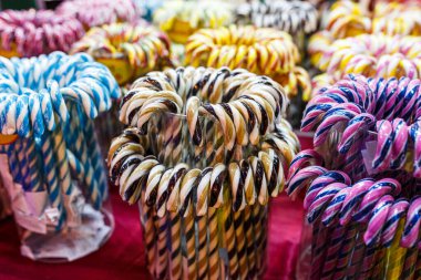 Noel ışıkları arka planında çok renkli baston şekerler. Noel panayırında lolipoplar, kış tatilleri. Kapat..