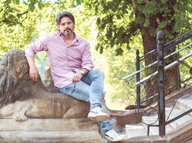 Bir parkta oturan yetişkin adam. Toplam veya tam uzunluğu kişi doğada, açık