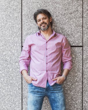 Casual adam gri duvar önünde çapraz kolları olan. Gülümseyen neşeli işadamı